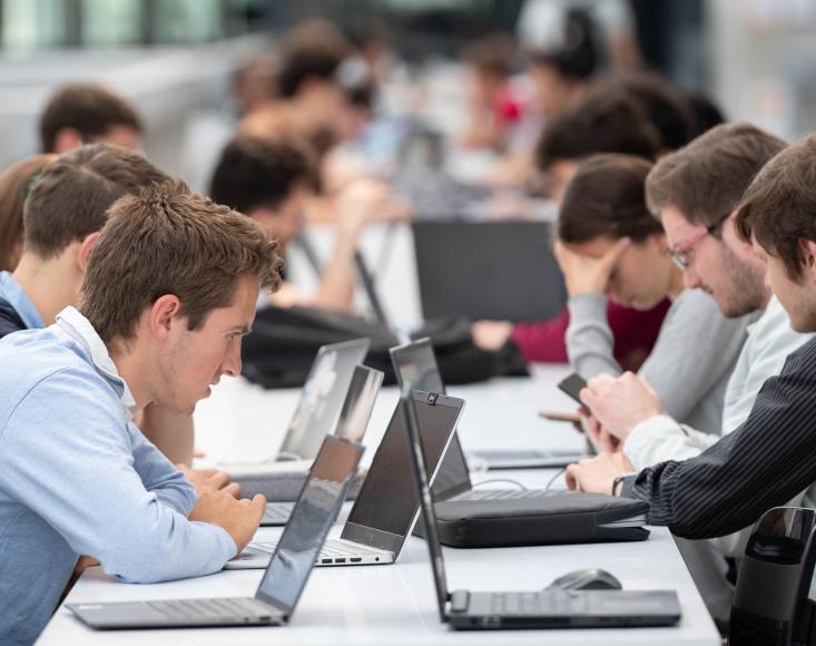 des étudiants révisant sur des tables devant leur ordinateur